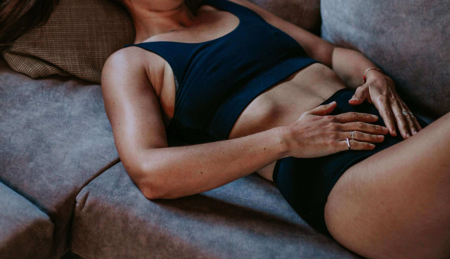 אישה לובשת תחתוני מחזור שוכבת על ספה לנוחות והגנה בזמן המחזור