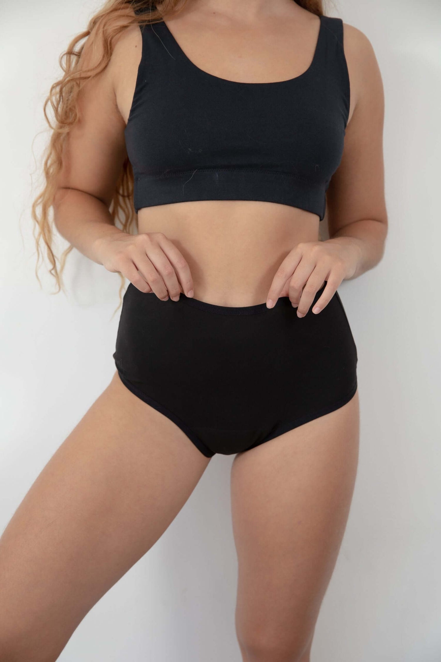 אישה לובשת תחתוני מחזור שחורים וחזייה תואמת, מראה נוחות וביטחון בשגרת היומיום שלה